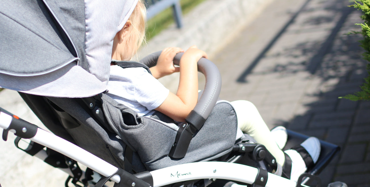 A modern gray and black baby stroller with a canopy, padded seat, safety harness, footrest, and large wheels, designed for comfort and safety.